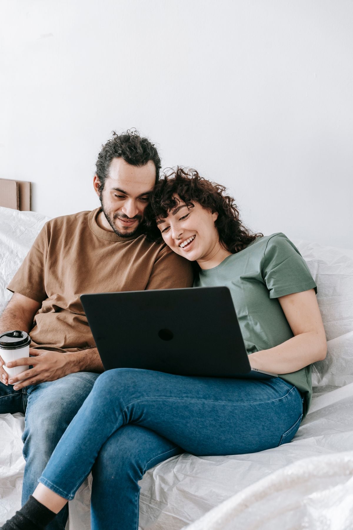 A couple sharing a laptop at home on a sofa